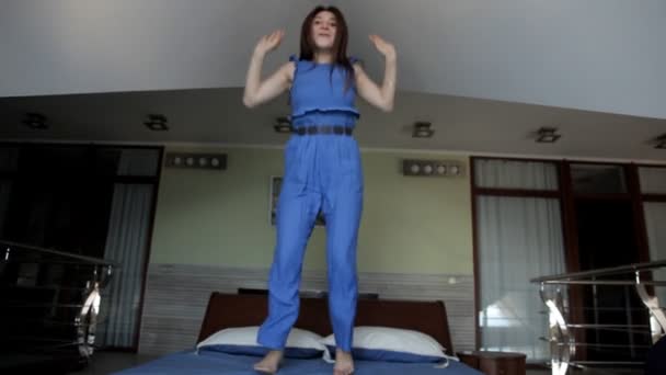 Chica joven como un niño feliz saltando sobre la cama — Vídeo de stock