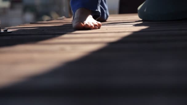 Una chica camina por el suelo de una terraza de madera — Vídeos de Stock