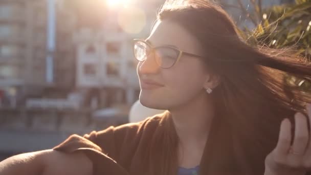 Flickan på kvällen solnedgången sitter på terrassen på ett café med utsikt över havet och staden. Romantisk kväll — Stockvideo