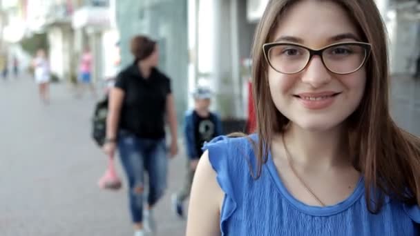 Дівчина гуляє по місту, розташованому на пляжі, посміхаючись і позуючи для камери — стокове відео