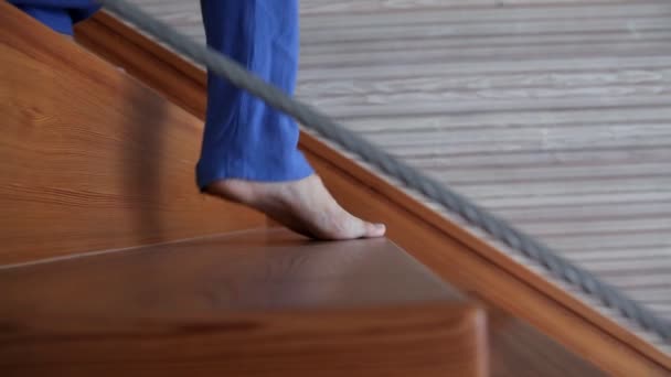 Una joven en su casa está caminando sobre una hermosa escalera de madera — Vídeos de Stock