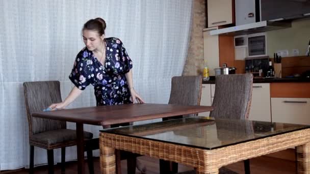 Young girl cleans up in the kitchen in the morning wipes the table after breakfast — Stock Video