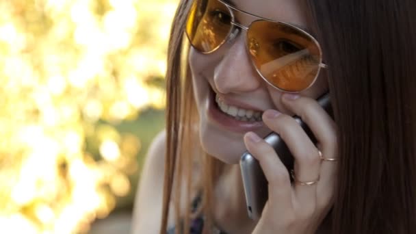 Una joven caminando por el parque hablando por teléfono — Vídeos de Stock