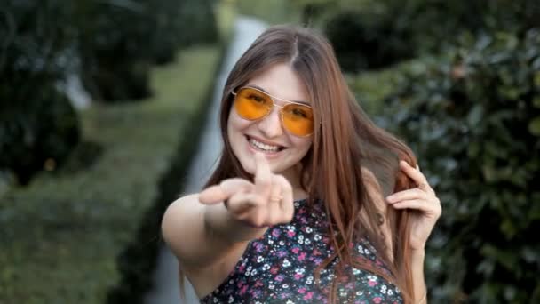 A young girl in a beautiful green park poses for the camera and then merrily runs off — Stock Video