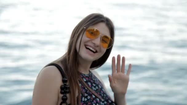 Cute girl strolling by the sea at sunset posing on camera — Stock Video