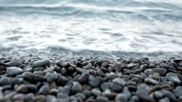 Маленькие волны моря на берегу покрывают небольшие камни — стоковое видео