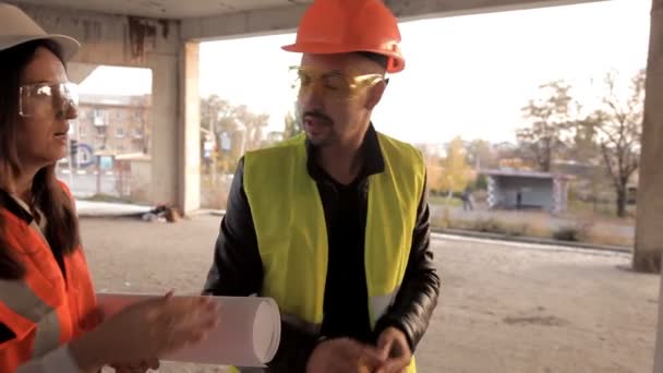 Der Entwickler zeigt seinen Kunden, wie sich die Konstruktion ihres Objekts bewegt, diskutiert die Details, trägt spezielle Kleidung und Helme — Stockvideo