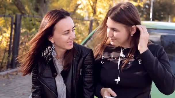 Duas mulheres falando de pé no capô de um carro verde estacionado — Vídeo de Stock