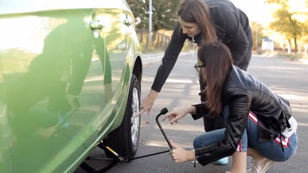 彼の車のタイヤを変えることを学ぶ 道路の側の女の子 — ストック動画