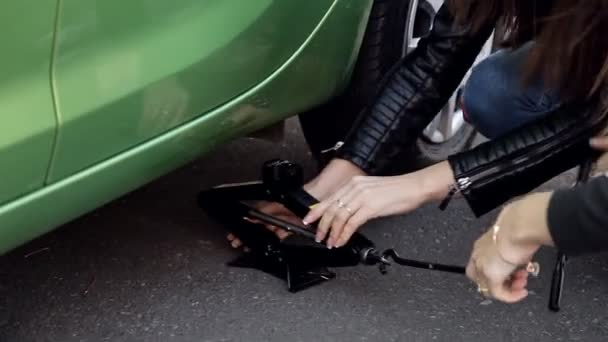 Κορίτσια μαθαίνουν στην πλευρά του δρόμου για να αλλάξετε το ελαστικό για το αυτοκίνητό του — Αρχείο Βίντεο