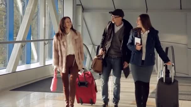 Zwei Mädchen und ein Mann treffen sich am Flughafen, bevor sie ins Flugzeug steigen — Stockvideo