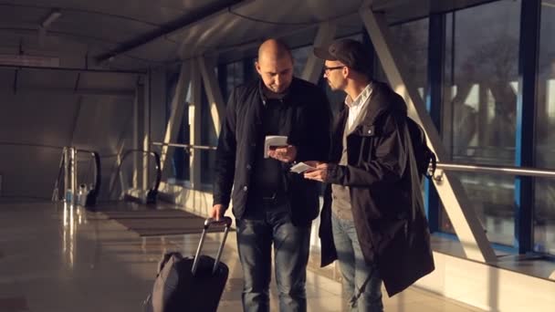 Deux hommes à l'aéroport essayant de trier les documents et de trouver la porte requise — Video