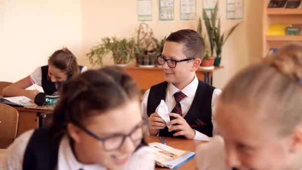 Jongen in uniform op school in de klas maakt het papier vliegtuig — Stockvideo