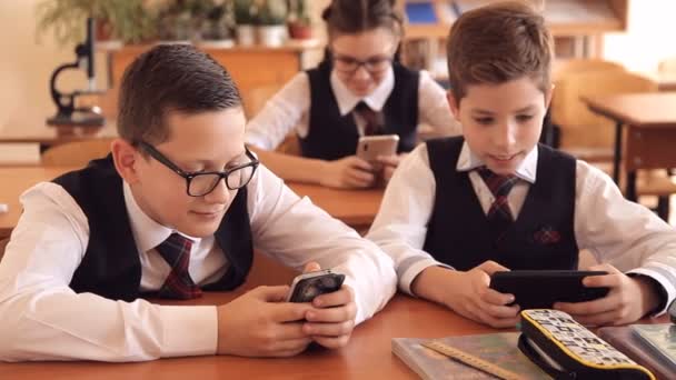 Estudiante durante una lección, jugando en un smartphone, escondiéndose de la maestra — Vídeo de stock