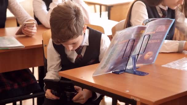 Étudiant pendant un cours, jouant sur un smartphone, se cachant de l'enseignant — Video