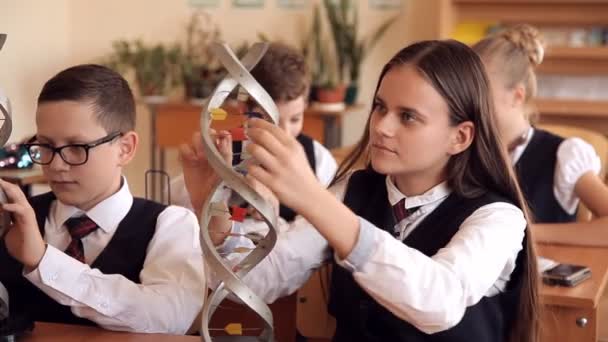 Escolares en uniforme escolar están estudiando el diseño del ADN sentado en el aula — Vídeo de stock