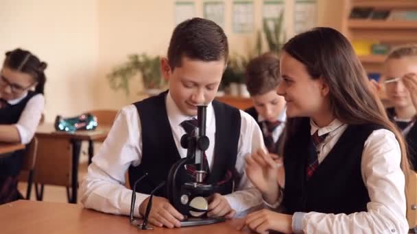 Estudiantes universitarios en uniforme escolar con microscopio de trabajo sentados en el aula. El concepto de educación escolar — Vídeo de stock