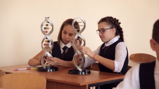 Escolares en uniforme escolar están estudiando el diseño del ADN sentado en el aula — Vídeos de Stock