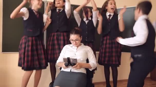 Pupils in school uniform are standing near a teacher who is sitting on a chair playing games on the phone. Concept of school education — Stock Video