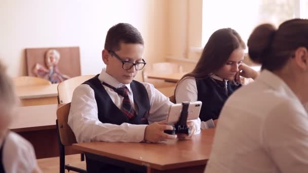 Student tijdens een les, spelen op een smartphone, het verbergen van de leraar — Stockvideo