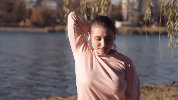 女の子が川の背景に公園でヨガ — ストック動画