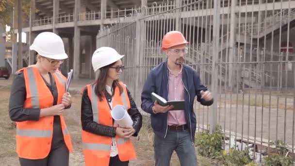 Dos mujeres y un hombre constructores están comprobando la construcción — Vídeos de Stock