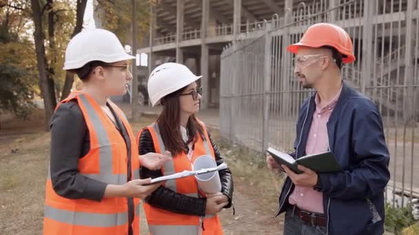 Dos mujeres y un hombre constructores están comprobando la construcción — Vídeos de Stock