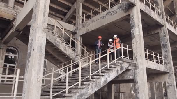Två kvinnor och en man byggare checkar byggandet — Stockvideo