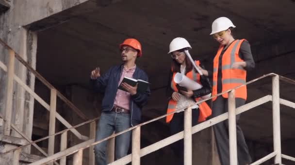 Duas mulheres e um homem construtores estão verificando a construção — Vídeo de Stock