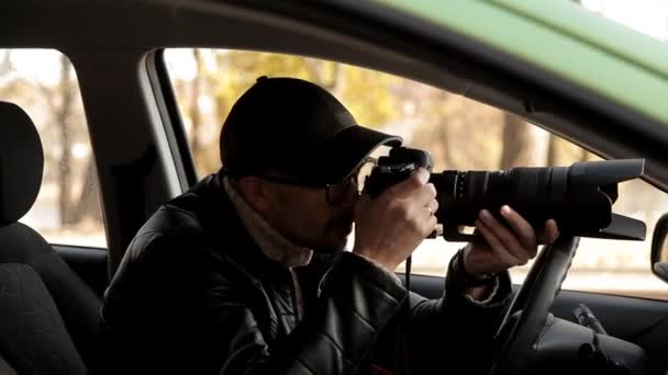 Un detective privado o un espía lleva a cabo la vigilancia del objeto de vigilancia. Un hombre tomando fotos en secreto desde la ventana del coche — Vídeos de Stock