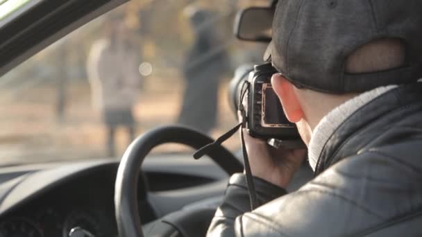 Έναν ιδιωτικό ντετέκτιβ ή ένα κατάσκοπος ασκεί εποπτεία του αντικειμένου της επιτήρησης. Ένας άνθρωπος που κρυφά λαμβάνοντας εικόνες από το παράθυρο του αυτοκινήτου — Αρχείο Βίντεο
