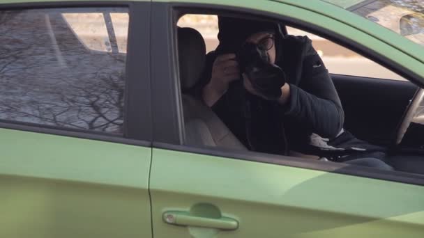 Um detetive particular ou um espião conduz a vigilância do objeto de vigilância. Um homem secretamente tirando fotos da janela do carro — Vídeo de Stock