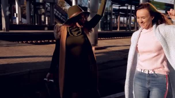 Duas meninas na estação ferroviária com suas malas na plataforma esperando o trem — Vídeo de Stock