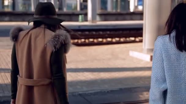 Due ragazze alla stazione ferroviaria con le valigie sul marciapiede in attesa del treno — Video Stock