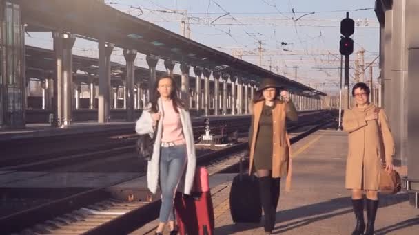 Пасажири з валізами ходять на платформі залізничного вокзалу. Три жінки з валізами, що ходять на платформі залізничного вокзалу — стокове відео