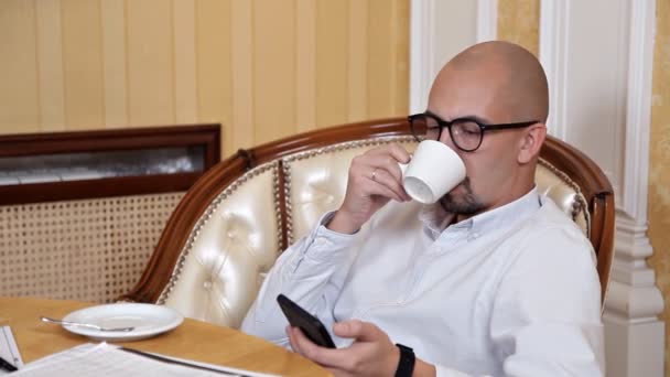 Glatzkopf am Tisch in seinem Büro beim Kaffeetrinken — Stockvideo