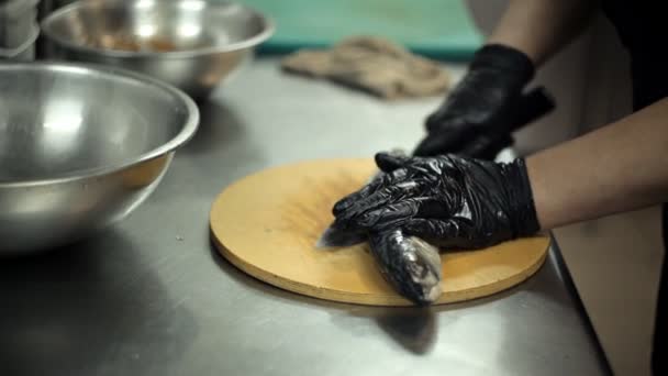 Нарезание рыбы острым ножом на доске на кухне — стоковое видео