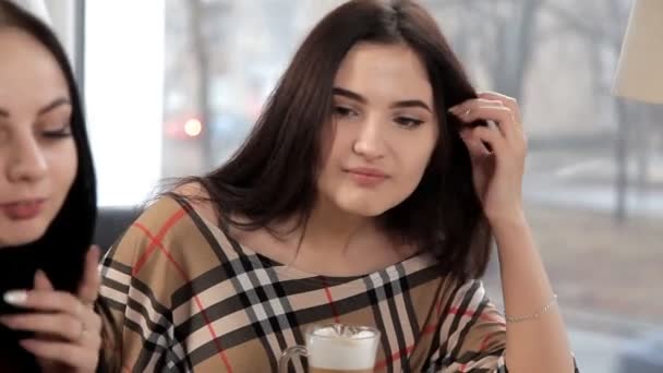 Fyra flickor dricker en latte eller kaffe på ett kafé skrattar och pratar. Möhippa med kaffe. fika — Stockvideo