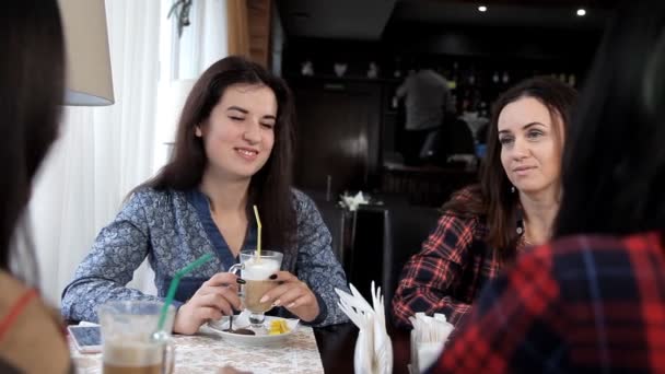 Cuatro chicas beben un café con leche o café en un café riendo y hablando. despedida de soltera con café. pausa para el café — Vídeos de Stock