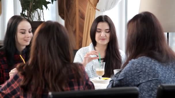 Quatro meninas bebem um café ou um café em um café rindo e conversando. despedida de solteira com café. coffee-break — Vídeo de Stock
