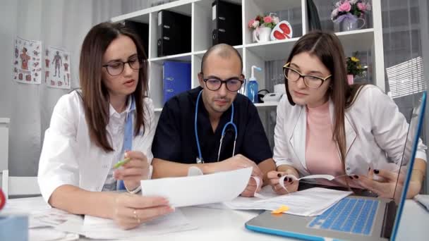 Het team van artsen onderzoekt de resultaten van het analyseren van de patiënten in het kantoor — Stockvideo