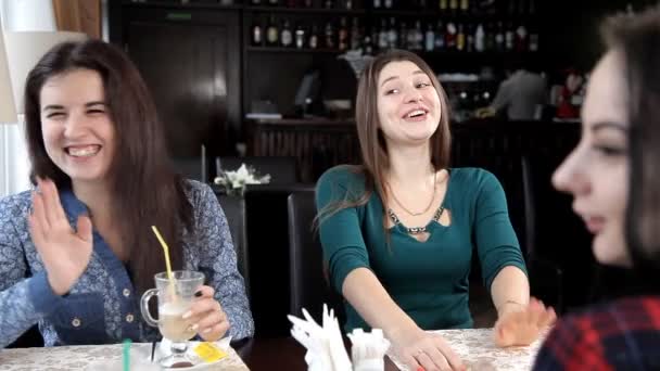 Fyra flickor dricker en latte eller kaffe på ett kafé skrattar och pratar. Möhippa med kaffe. fika — Stockvideo