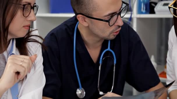 Equipe médica sentada e discutindo à mesa — Vídeo de Stock