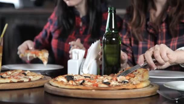 Varias chicas comen pizza y beben cerveza de botellas en el restaurante. Habla ríete y celebra — Vídeos de Stock