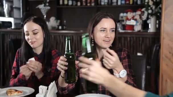 Several girls eat pizza and drink beer from bottles in the restaurant. Talk laugh and celebrate — Stock Video