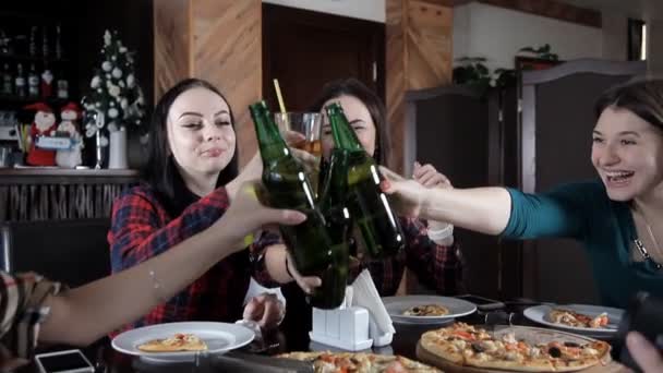Plusieurs filles mangent de la pizza et boivent de la bière dans les bouteilles du restaurant. Parler rire et célébrer — Video