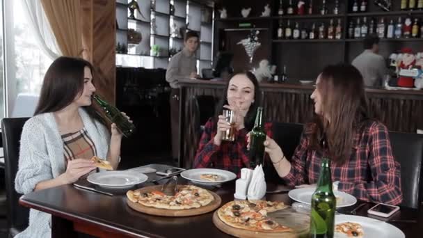 Birkaç kız pizza yemek ve restoran şişelerde üzerinden bira içmek. Kahkaha konuşmak ve kutlamak — Stok video