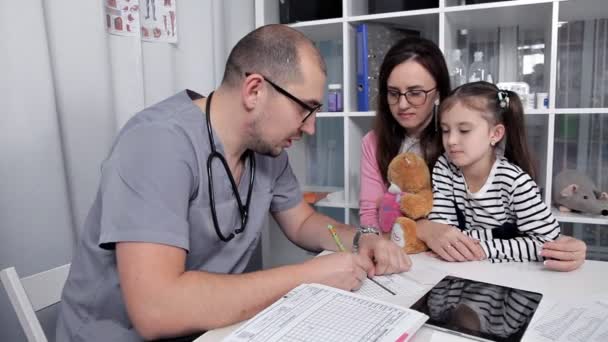 Na bestudering van het kind, schrijft de arts medicatie en de noodzakelijke proeven — Stockvideo