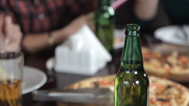 Várias meninas comem pizza e bebem cerveja de garrafas no restaurante. Fale rir e comemorar — Vídeo de Stock