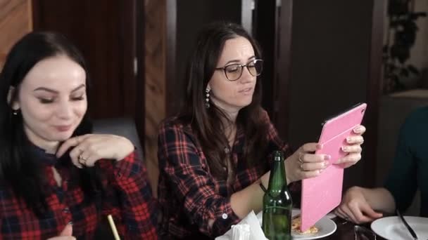 Varias chicas comen pizza y beben cerveza de botellas en el restaurante. Habla ríete y celebra — Vídeo de stock